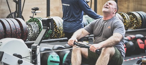 A 180 Project athlete is straining as he uses a rowing machine.